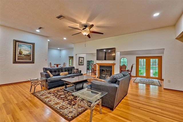 living room with light hardwood / wood-style flooring, ceiling fan, and french doors