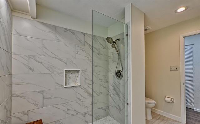 bathroom featuring a tile shower, hardwood / wood-style flooring, and toilet