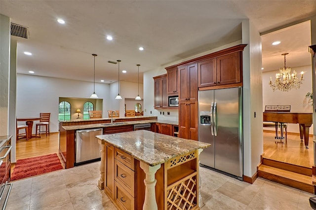 kitchen with pendant lighting, kitchen peninsula, a notable chandelier, and built in appliances