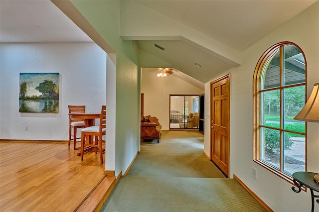 corridor featuring light wood-type flooring and vaulted ceiling