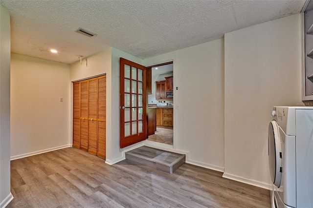 interior space featuring washer / clothes dryer, a textured ceiling, and light wood-type flooring