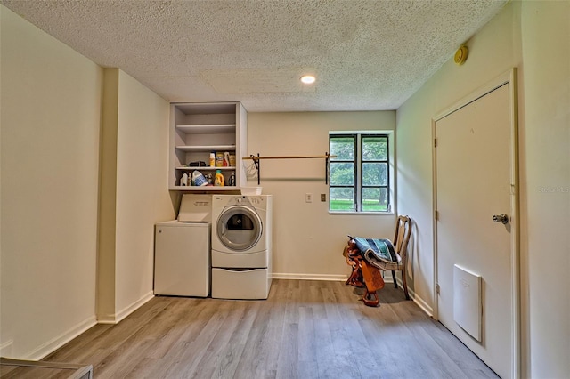 laundry room featuring a textured ceiling, light wood-type flooring, and washing machine and clothes dryer