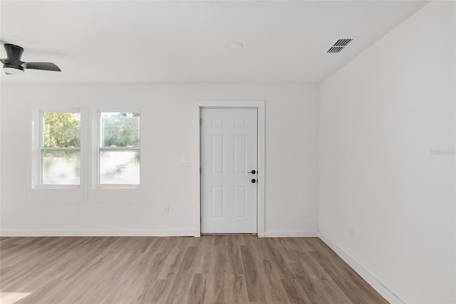 empty room featuring ceiling fan, wood finished floors, visible vents, and baseboards