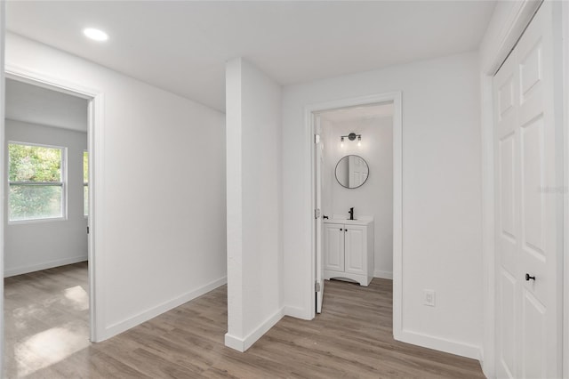 hallway with recessed lighting, light wood-type flooring, and baseboards