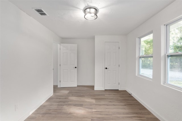 unfurnished room featuring light wood-style floors, baseboards, and visible vents