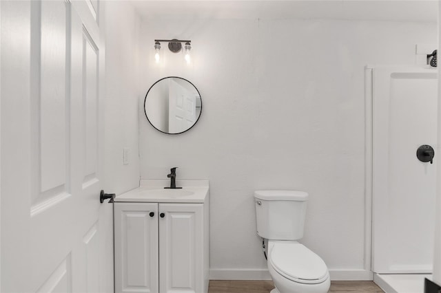 bathroom with baseboards, vanity, toilet, and wood finished floors