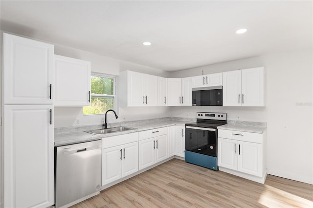 kitchen featuring light wood finished floors, stainless steel appliances, light countertops, white cabinetry, and a sink