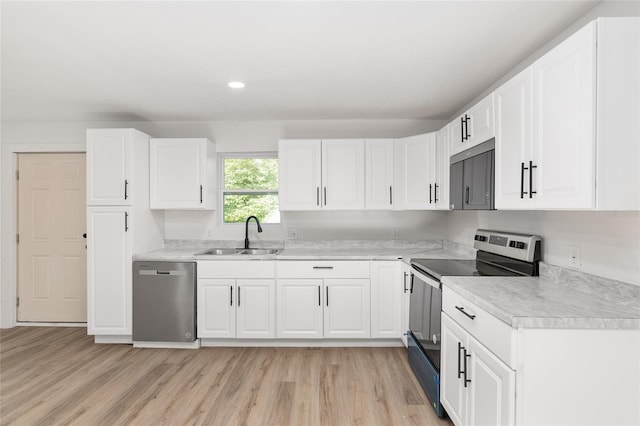 kitchen featuring white cabinets, stainless steel appliances, light countertops, light wood-style floors, and a sink