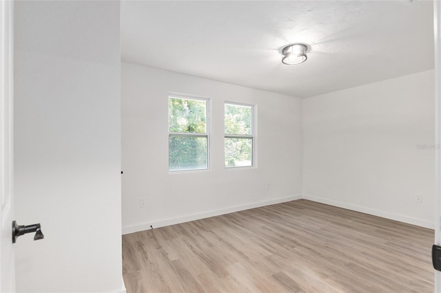 spare room with light wood-type flooring and baseboards