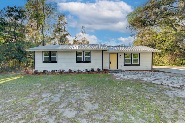 ranch-style home with metal roof and a front lawn