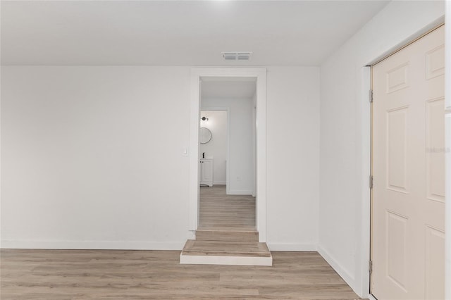 hall featuring light wood finished floors, visible vents, and baseboards