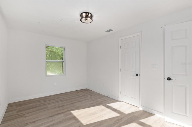 unfurnished room featuring light wood finished floors, visible vents, and baseboards