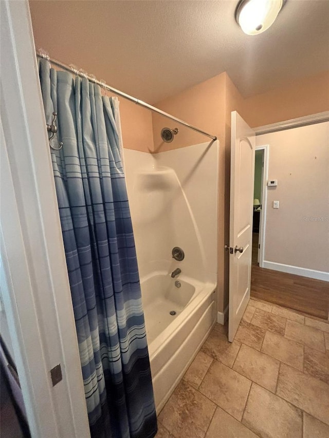 bathroom with a textured ceiling and shower / tub combo with curtain