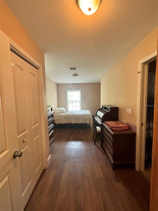 bedroom with dark hardwood / wood-style floors and a closet