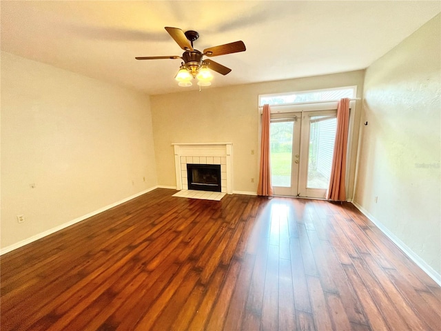 unfurnished living room featuring ceiling fan, a tiled fireplace, french doors, and wood-type flooring