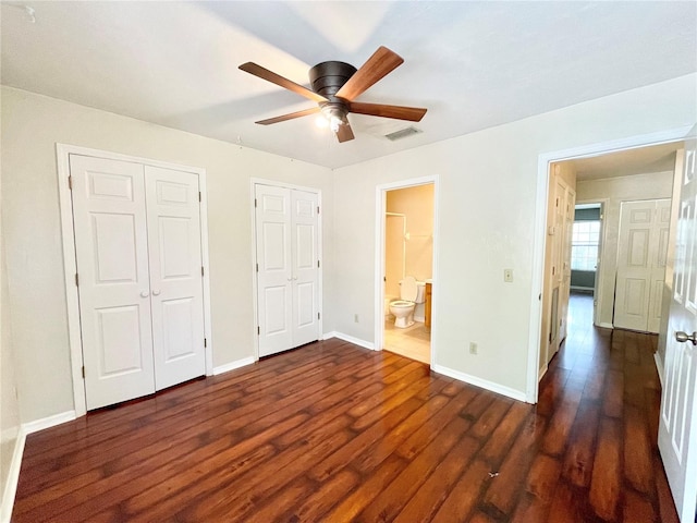 unfurnished bedroom featuring ceiling fan, multiple closets, ensuite bath, and dark hardwood / wood-style flooring