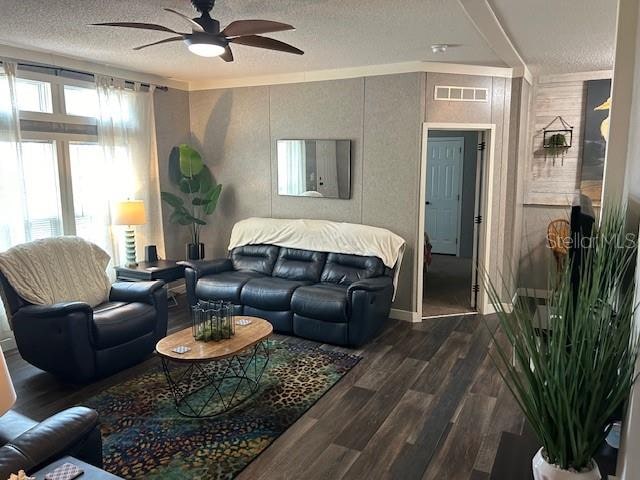 living room with ceiling fan, dark hardwood / wood-style floors, ornamental molding, and a textured ceiling