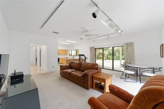 carpeted living room featuring ceiling fan, track lighting, and sink