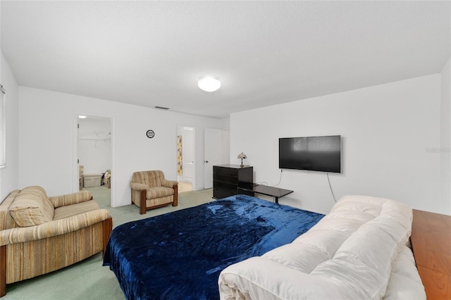 bedroom with a textured ceiling, carpet flooring, a spacious closet, and a closet