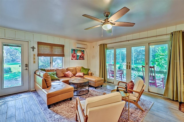 living room with french doors, a wall unit AC, ceiling fan, and hardwood / wood-style floors