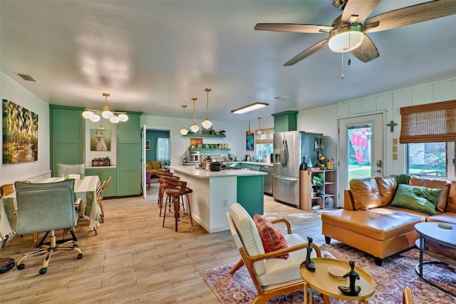 living room featuring ceiling fan with notable chandelier and light hardwood / wood-style floors