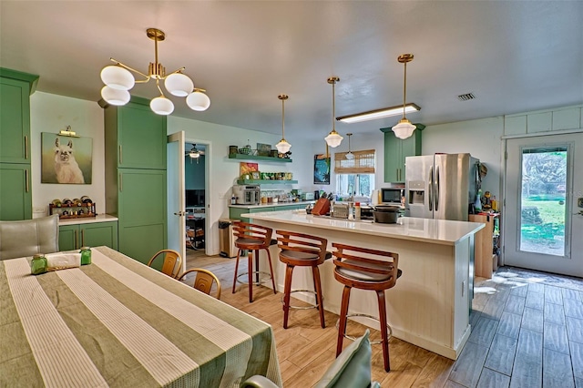 kitchen featuring pendant lighting, green cabinets, stainless steel fridge, and a healthy amount of sunlight