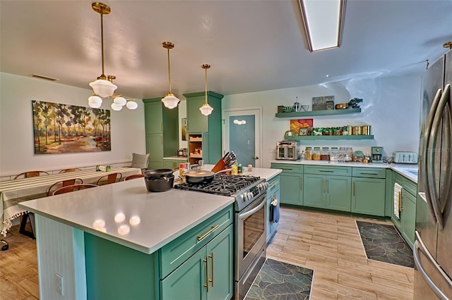 kitchen featuring light wood-type flooring, hanging light fixtures, a kitchen island, green cabinets, and appliances with stainless steel finishes