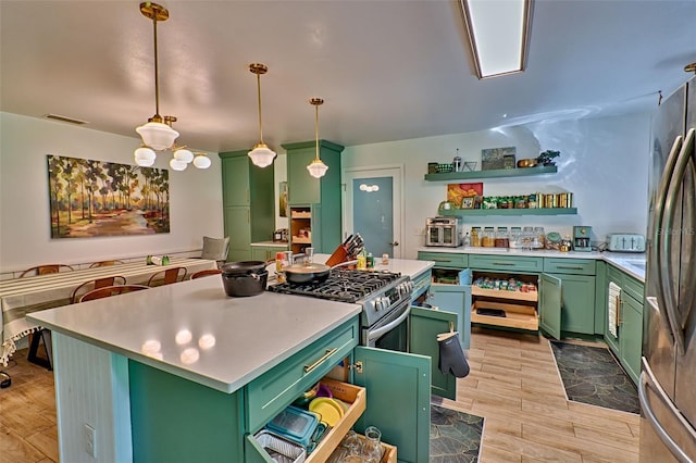 kitchen with hanging light fixtures, light hardwood / wood-style floors, green cabinetry, and stainless steel appliances