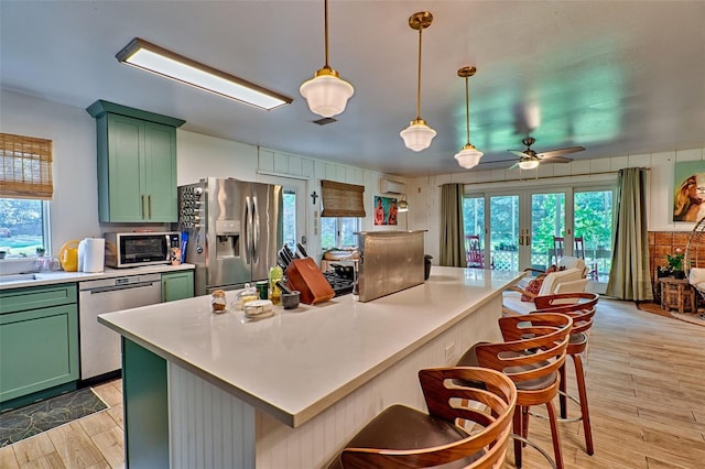 kitchen with pendant lighting, stainless steel appliances, light hardwood / wood-style floors, and ceiling fan