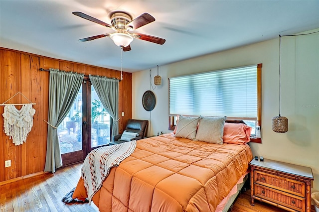 bedroom featuring wood-type flooring, wood walls, and ceiling fan