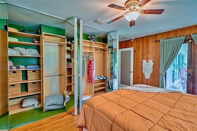 bedroom with wood walls, ceiling fan, and hardwood / wood-style flooring