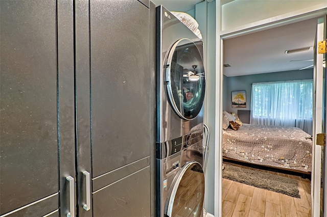 laundry room featuring stacked washer and dryer and hardwood / wood-style flooring