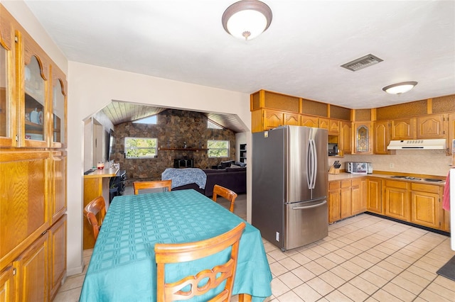 kitchen featuring cooktop, stainless steel fridge, vaulted ceiling, and light tile patterned floors