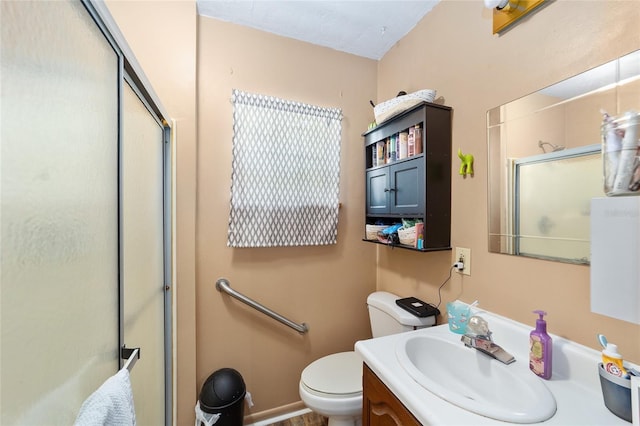 bathroom featuring a shower with door, vanity, and toilet