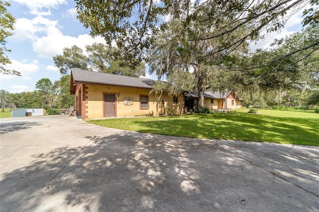 ranch-style home featuring a garage, an outdoor structure, and a front lawn