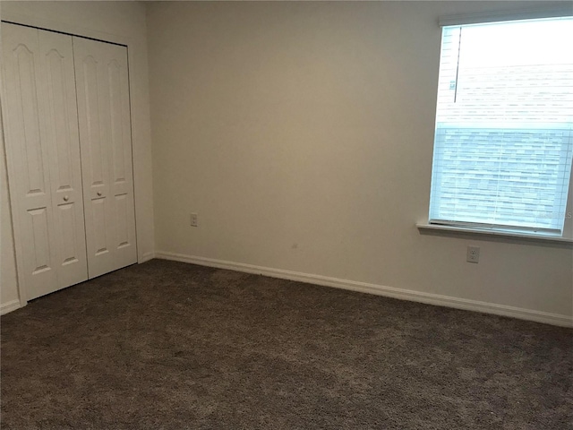 unfurnished bedroom with dark carpet and a closet