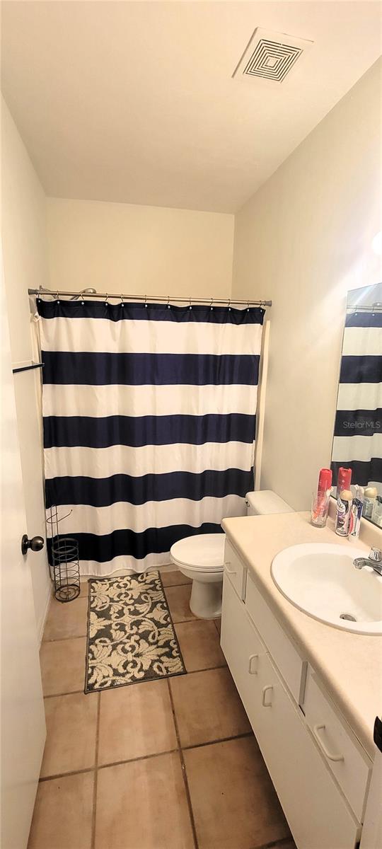 bathroom featuring a shower with shower curtain, tile patterned floors, vanity, and toilet