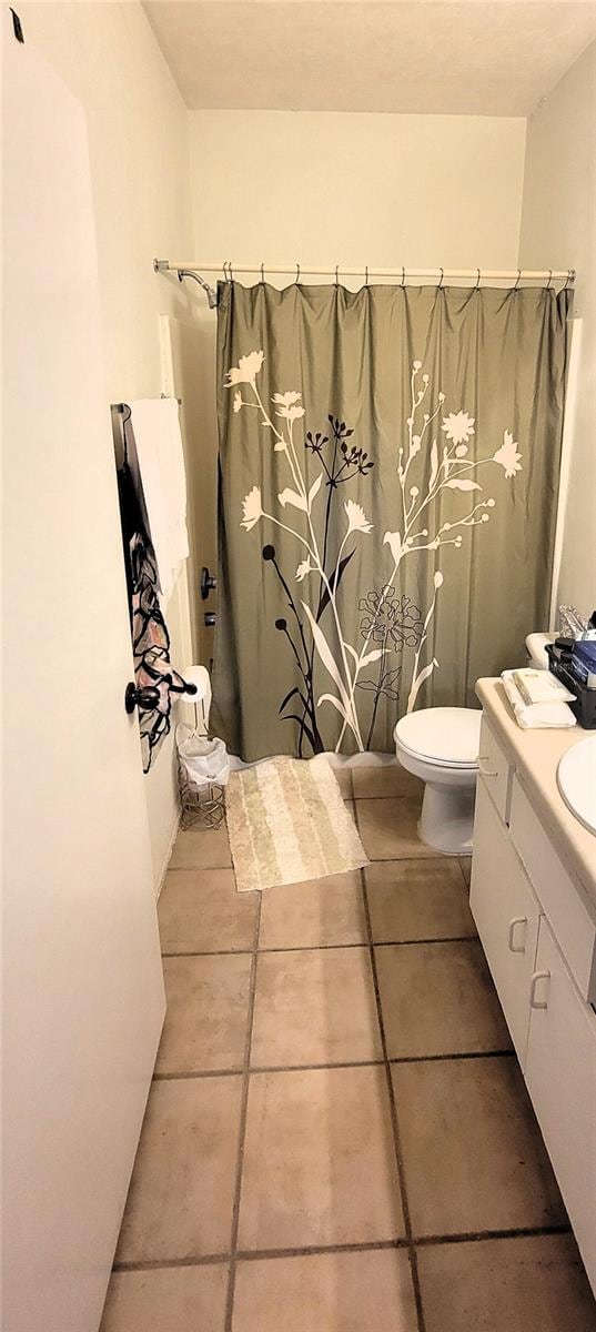 bathroom with tile patterned flooring, walk in shower, vanity, and toilet