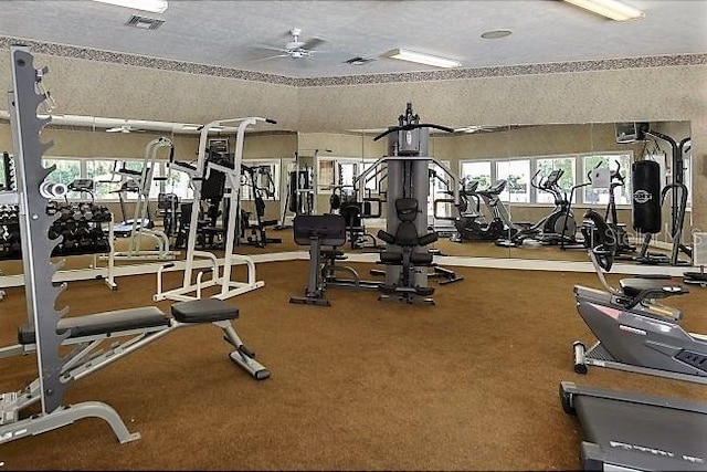 exercise room with ceiling fan and a textured ceiling