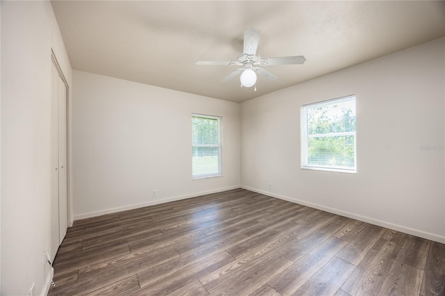 unfurnished room featuring ceiling fan, dark hardwood / wood-style floors, and a wealth of natural light