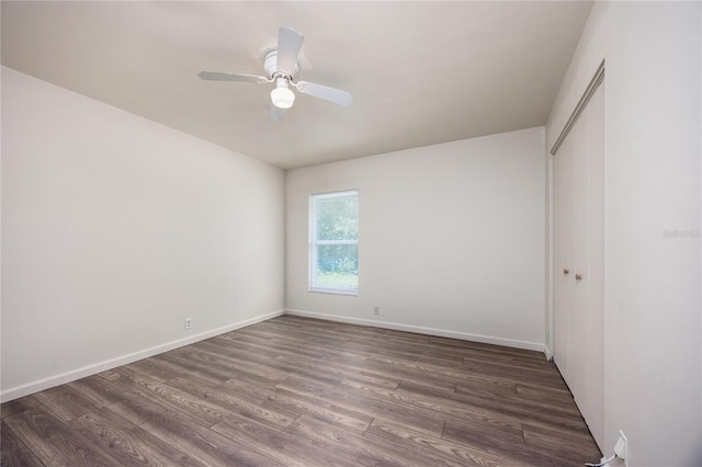 unfurnished bedroom with ceiling fan, a closet, and dark wood-type flooring