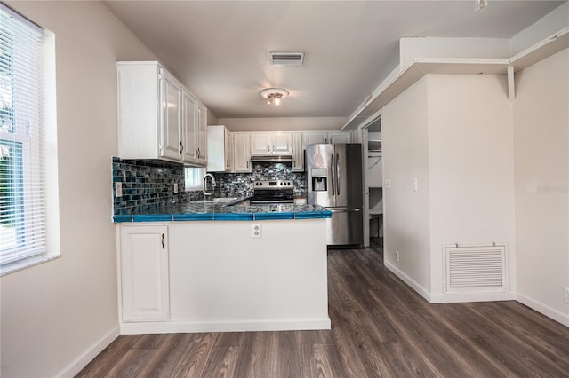 kitchen with appliances with stainless steel finishes, plenty of natural light, dark hardwood / wood-style floors, and white cabinetry