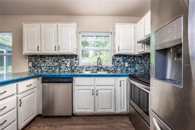 kitchen with white cabinets, sink, dark wood-type flooring, appliances with stainless steel finishes, and tile countertops