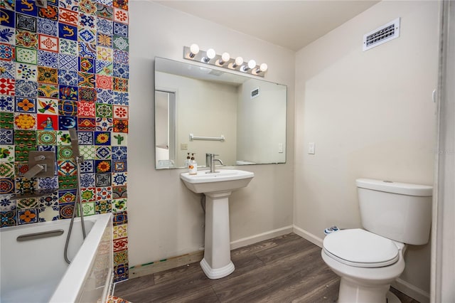 bathroom featuring hardwood / wood-style flooring, toilet, and a tub