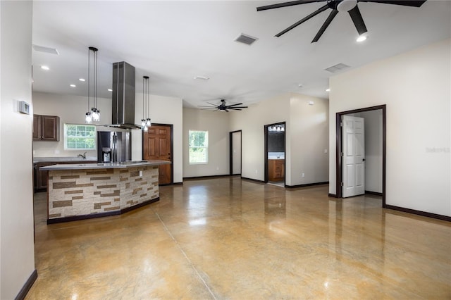 kitchen with island range hood, hanging light fixtures, a kitchen island, ceiling fan, and stainless steel fridge