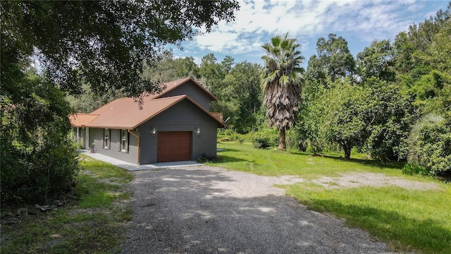131 Riley Lake Dr, Hawthorne, FL 32640 - view of front facade featuring gravel driveway, metal roof, a front yard, and a garage