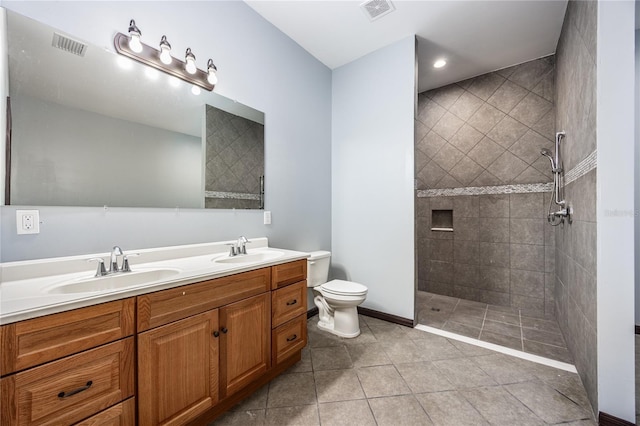 bathroom with tiled shower, vanity, toilet, and tile patterned flooring