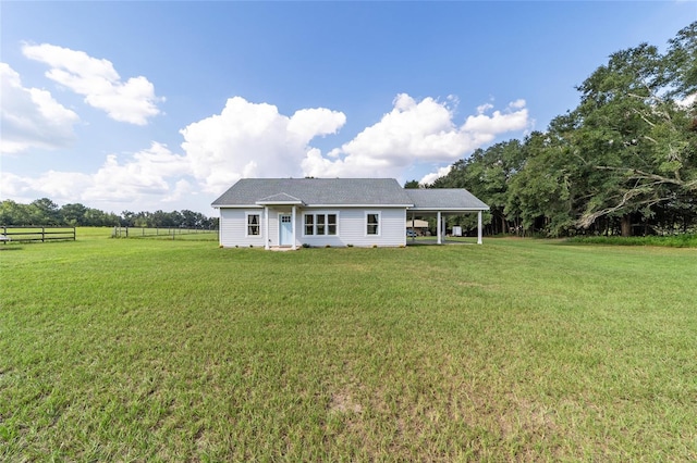 rear view of property with a rural view and a lawn