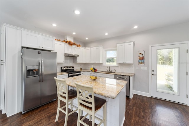 kitchen with dark hardwood / wood-style flooring, sink, stainless steel appliances, white cabinets, and a center island