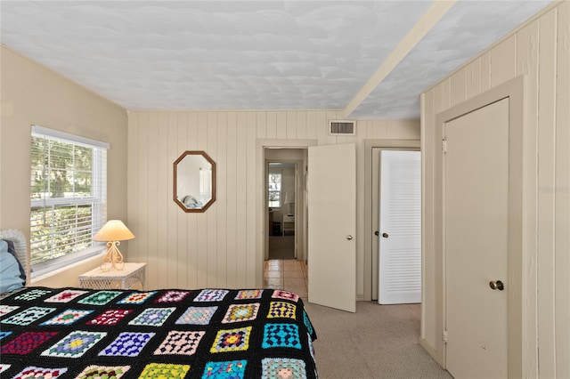 unfurnished bedroom with wooden walls and light carpet